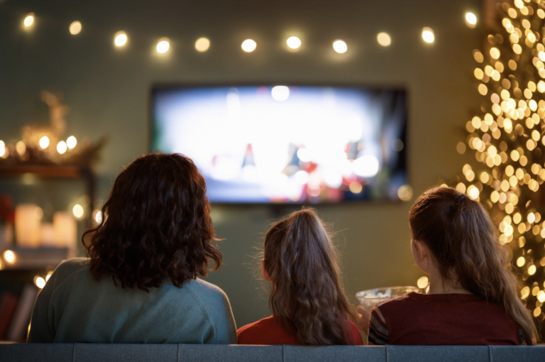 Family relaxing on a couch watching a movie together in a cozy living room